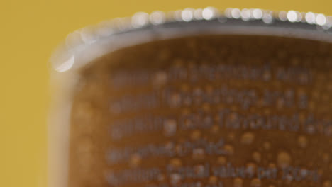 Close-Up-Of-Condensation-Droplets-On-Revolving-Takeaway-Can-Of-Cold-Beer-Or-Soft-Drink-Against-Yellow-Background